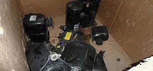 Black air conditioning compressors inside a cardboard box.