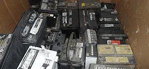 A pile of used car batteries in a storage container.