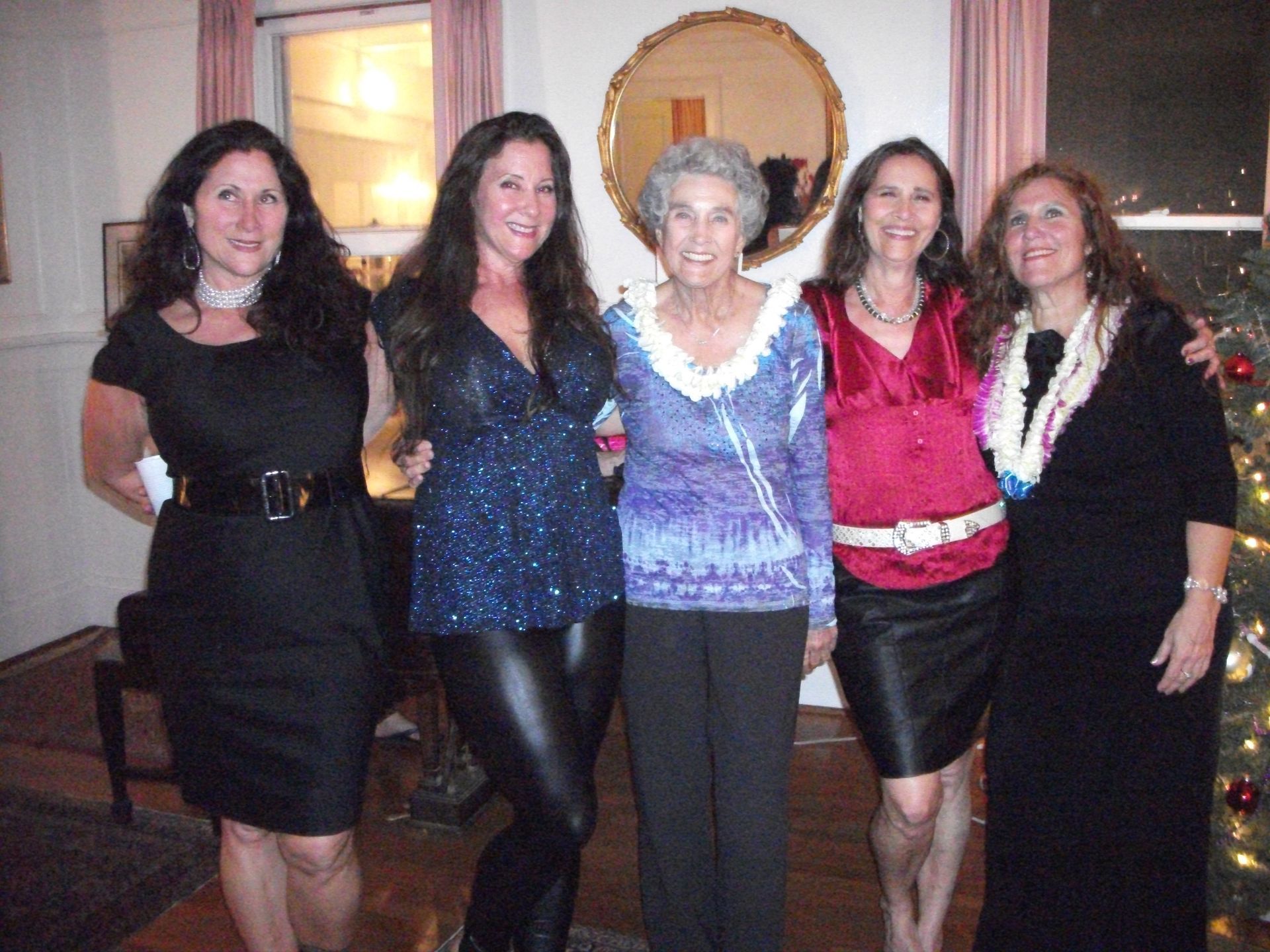 Five people posing together indoors; women in formal attire, smiles.