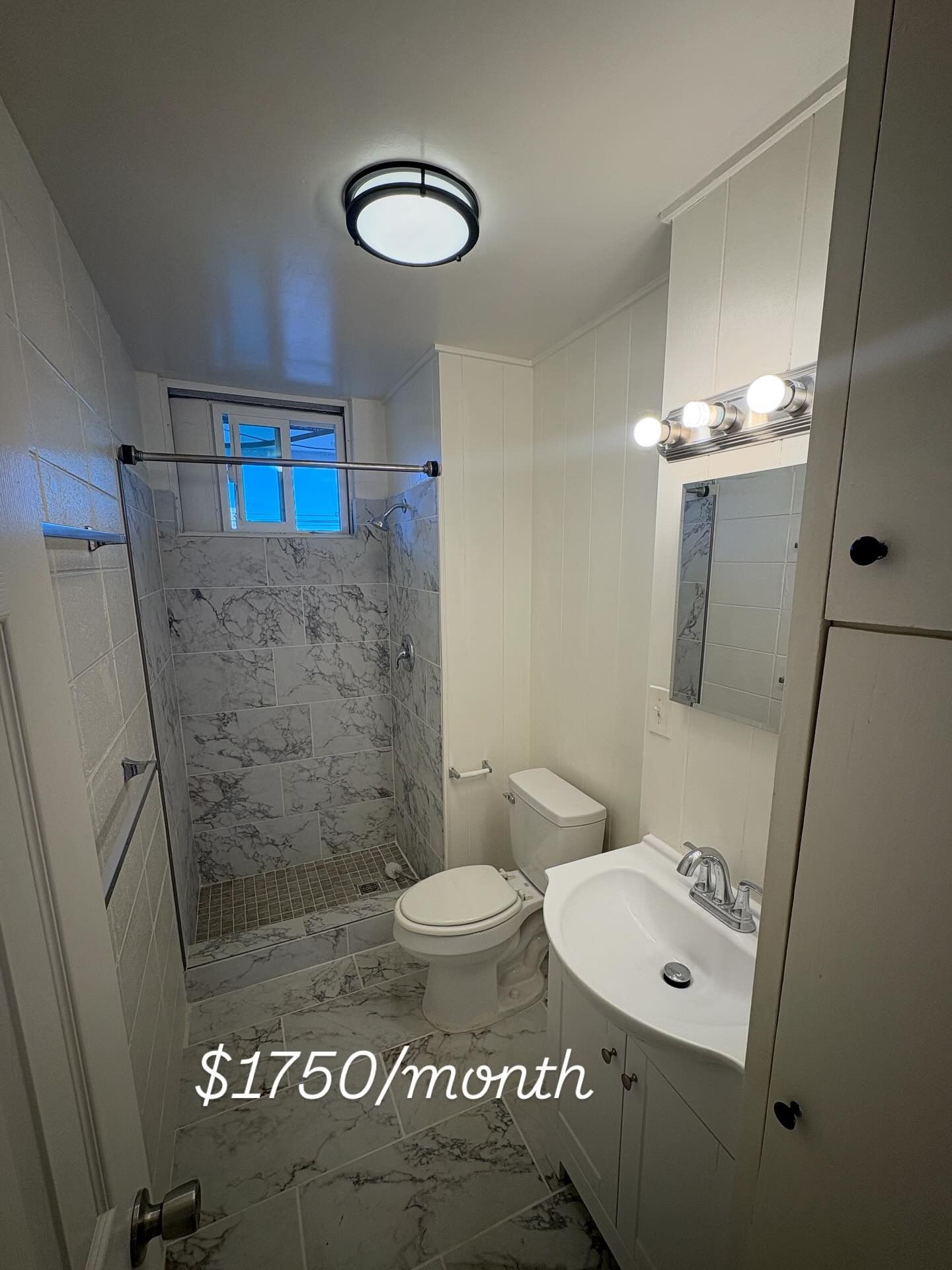 Small bathroom with marble-look shower and floor, white walls and sink, toilet, cabinet, and a $1750/month price.