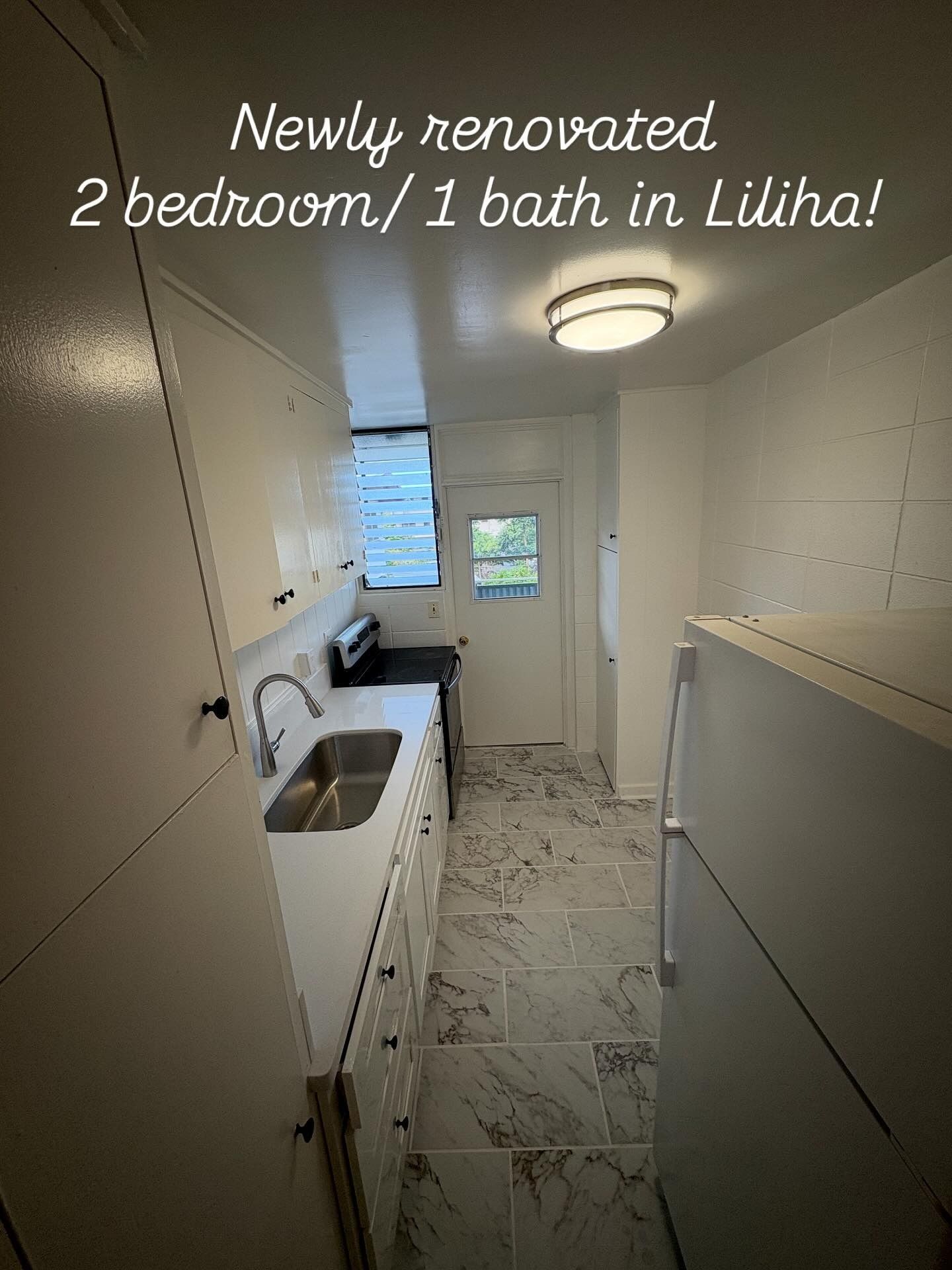 Newly renovated kitchen with white cabinets, stainless steel sink, and a refrigerator.