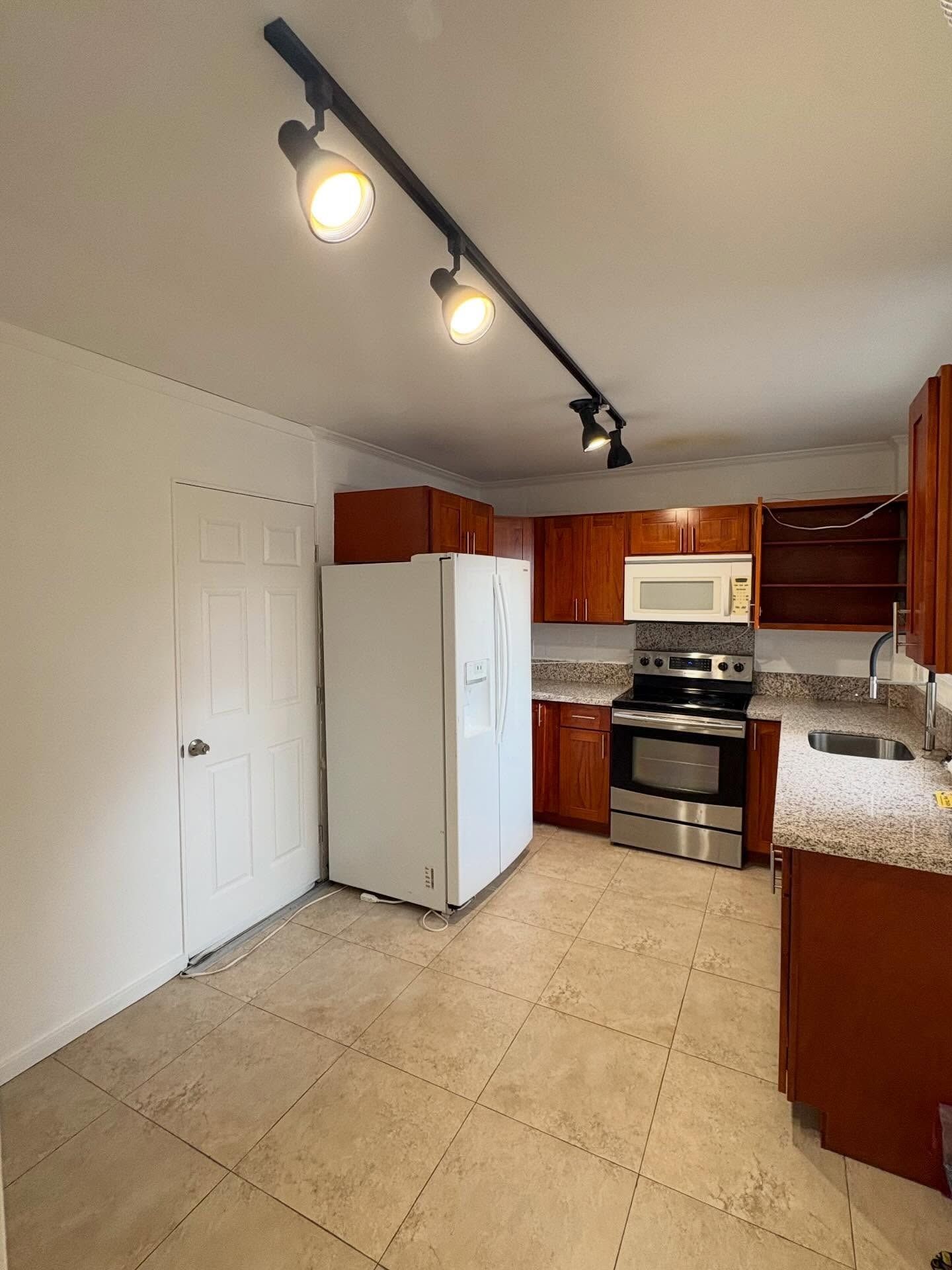 Kitchen with brown cabinets, white refrigerator, and stainless steel appliances.