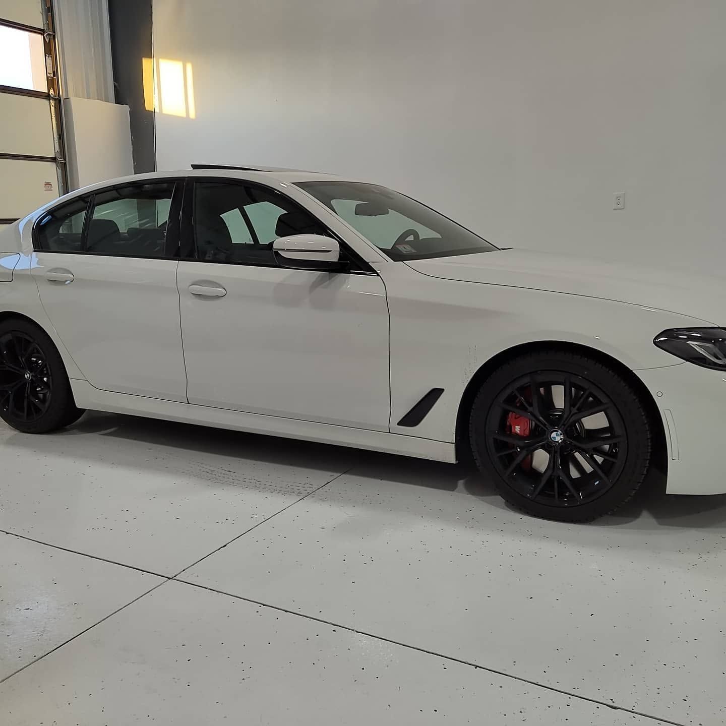 White sports sedan with black rims parked inside a bright garage, side view.