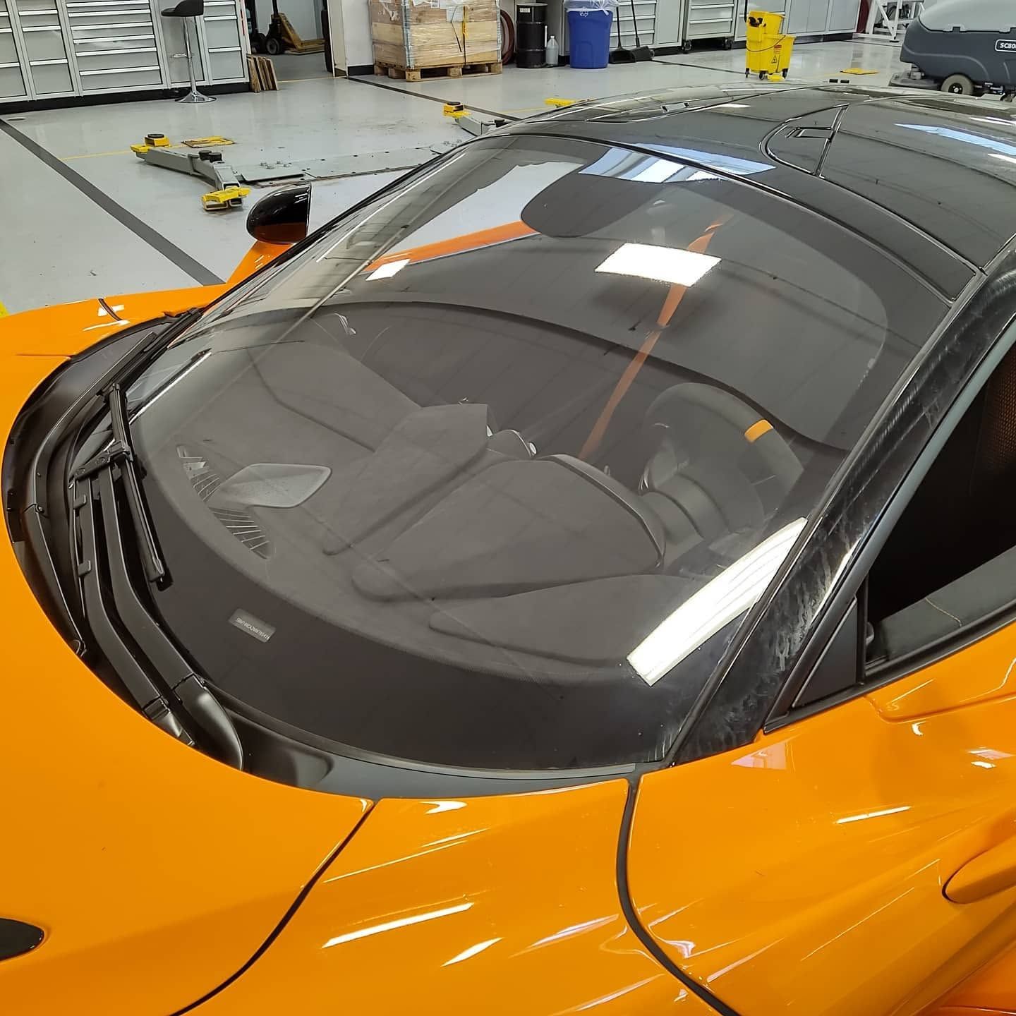Orange sports car in a garage, viewed from above through the windshield and roof.