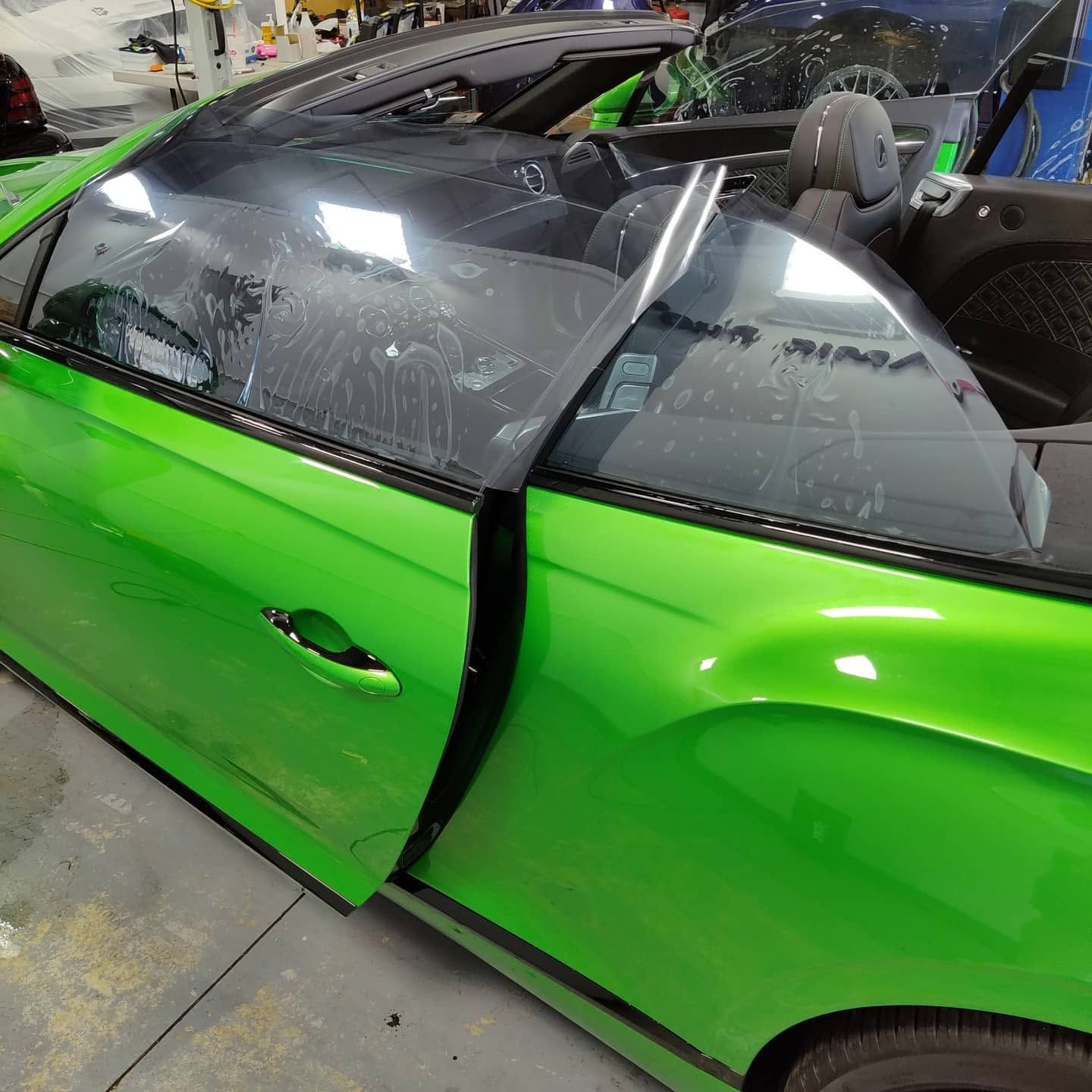 Bright green sports car with a shattered windshield and open door in a garage
