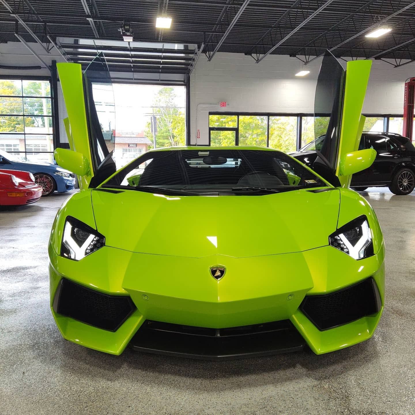 Bright green Lamborghini sports car in a showroom with scissor doors raised