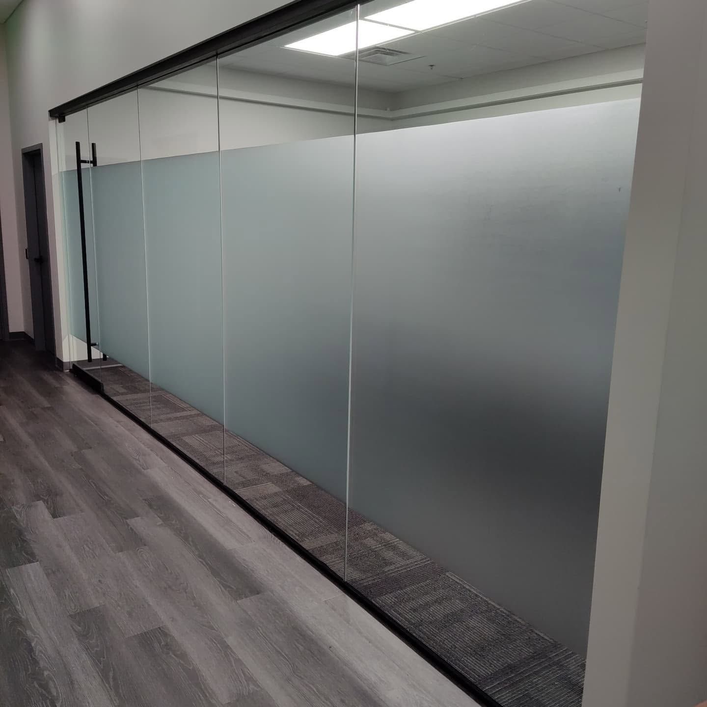 Modern office hallway with frosted glass walls and gray carpeted floor