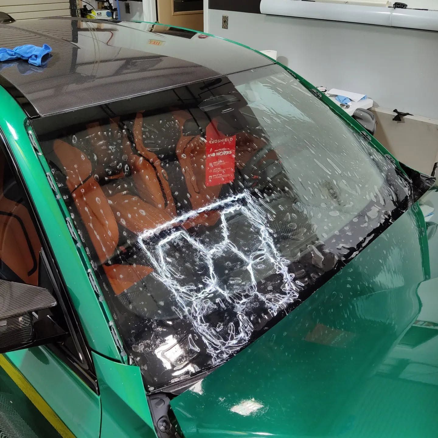 Green car windshield shattered by a large impact crack, with brown seats visible inside.