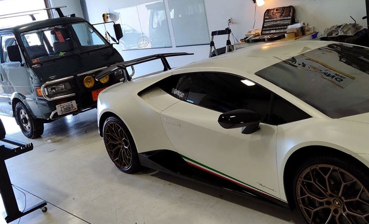 White sports car and black utility truck parked inside a garage or showroom.