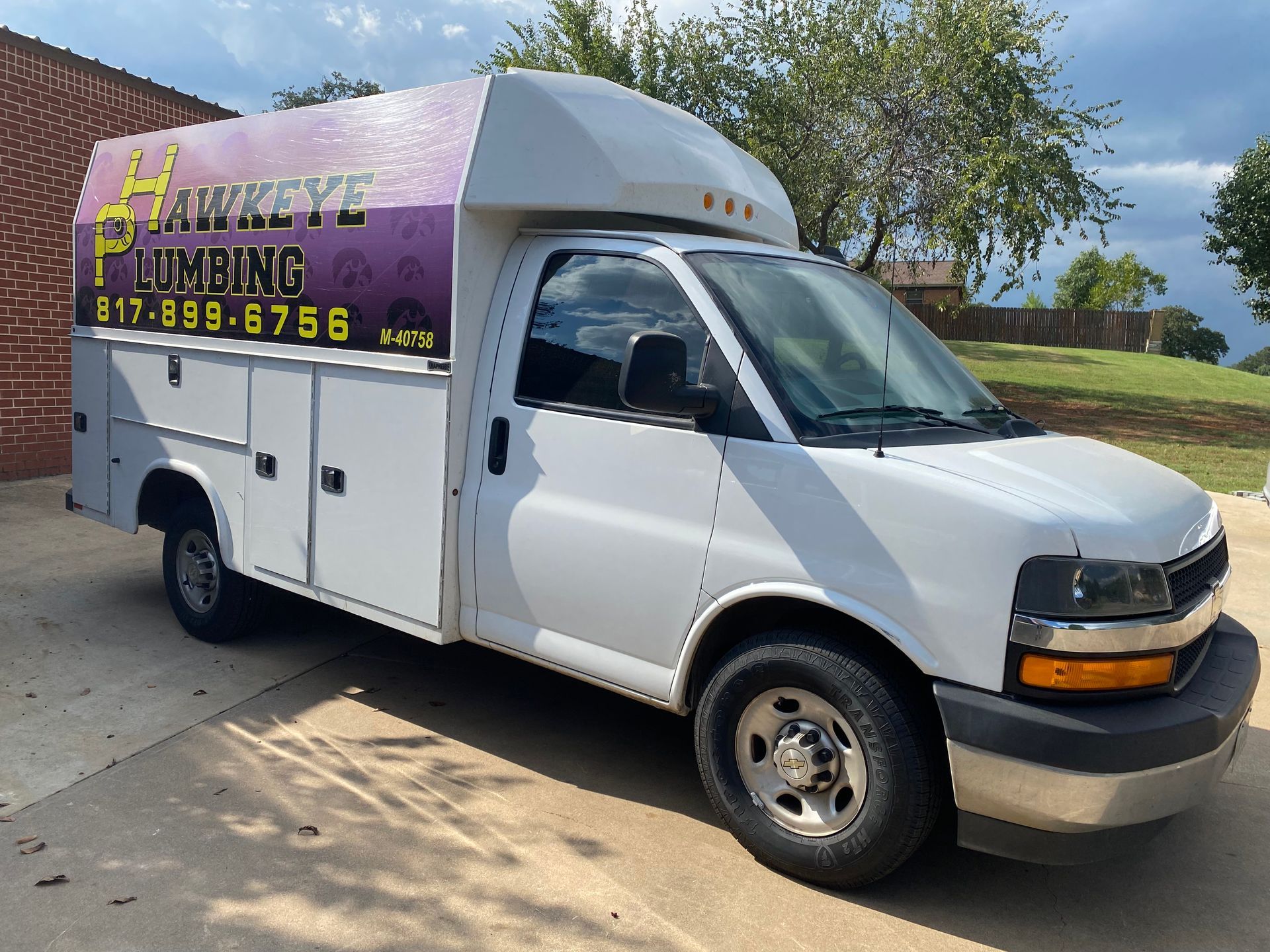 A hawkeye plumbing truck is parked in a driveway