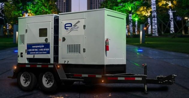 White towable generator trailer at night on a tree-lined road
