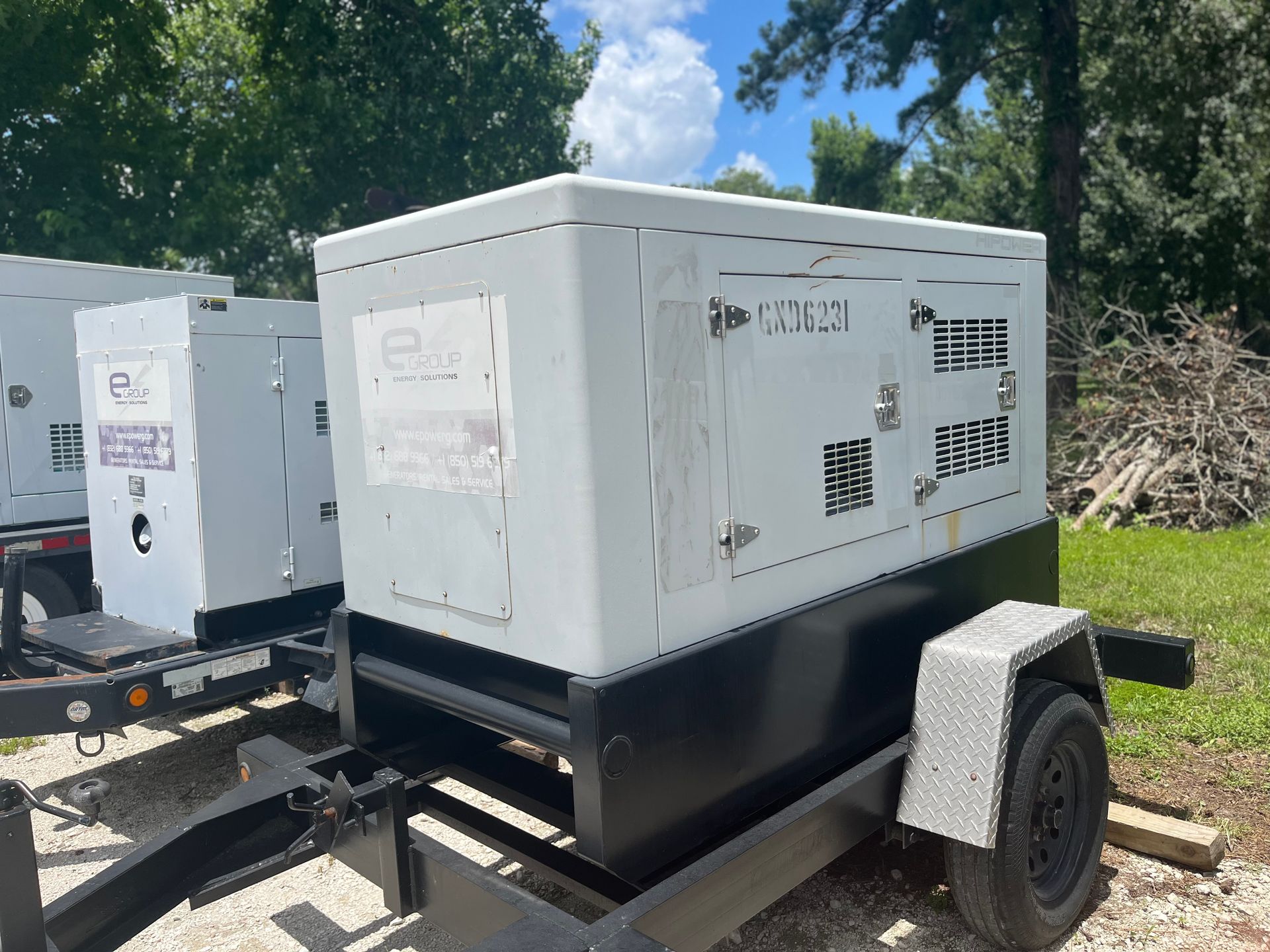 White industrial generator trailer parked outdoors beside another unit on a sunny day