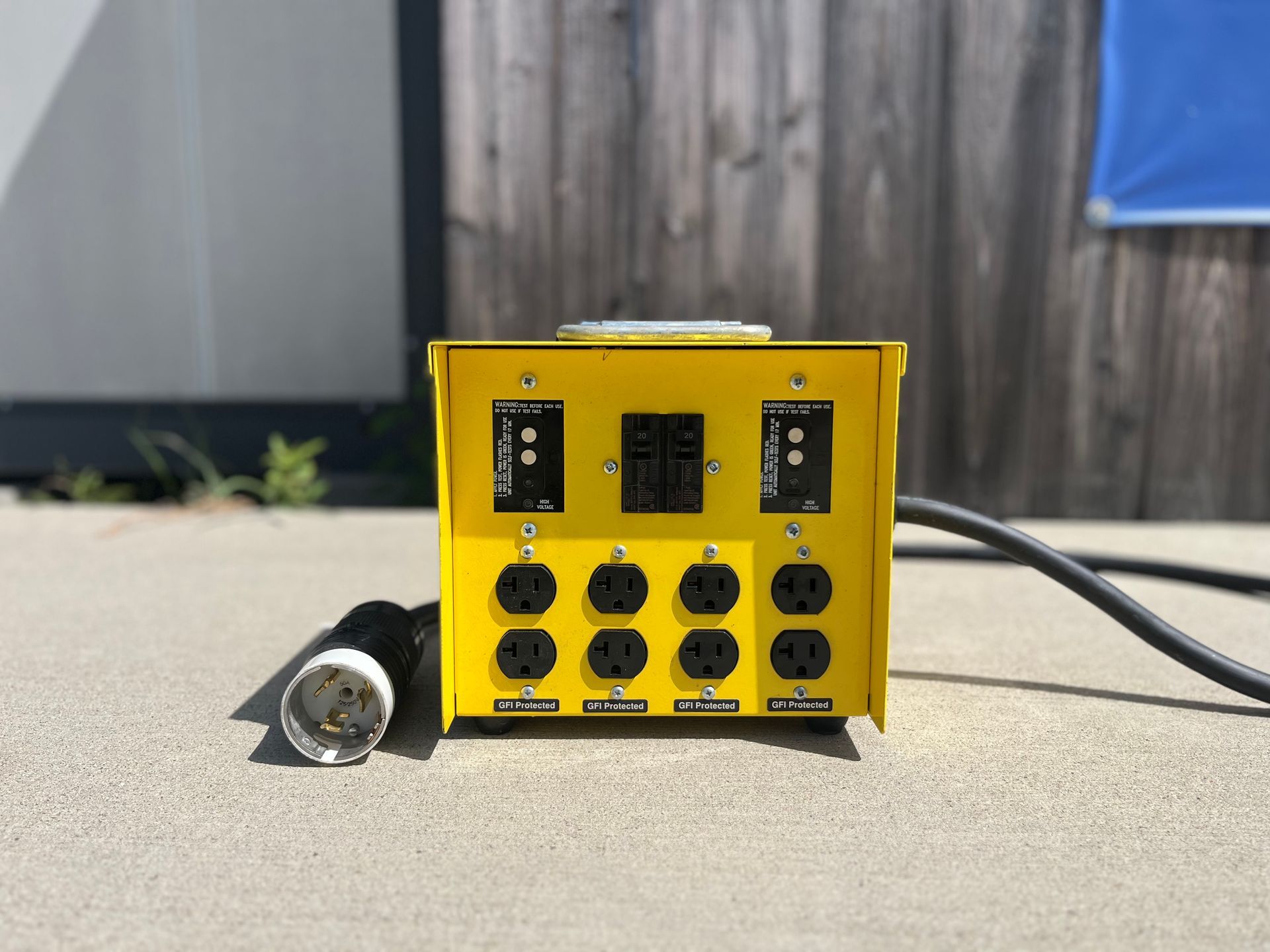 Yellow electronic control box with black knobs and switches on a concrete surface outdoors