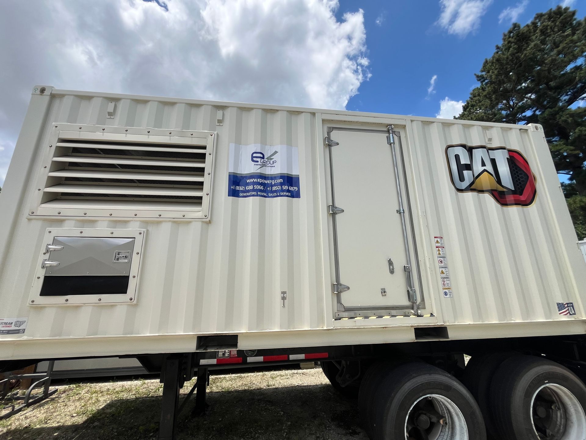 White CAT generator trailer on a truck bed under a blue sky with clouds