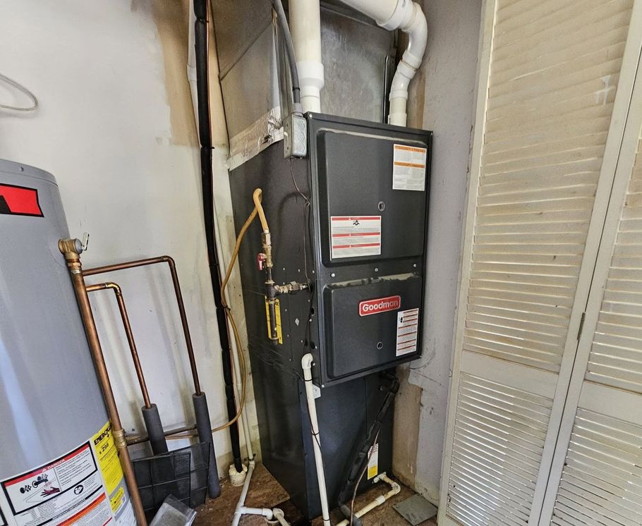 HVAC furnace and ductwork in a narrow utility closet beside a water heater