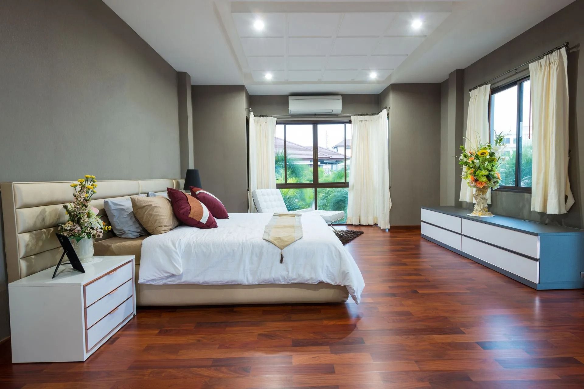 Spacious bedroom with hardwood floors, a large bed, and a long dresser.