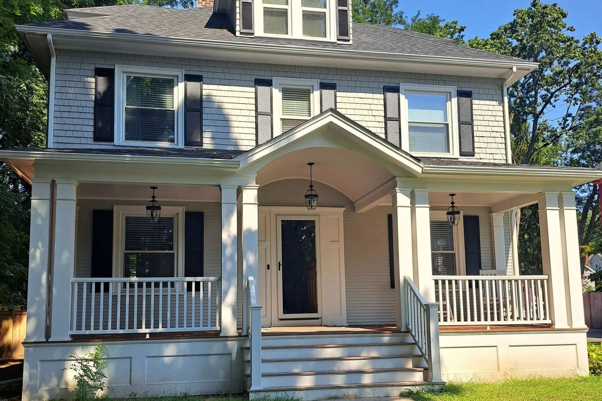 Two-story white house with front porch, blue shutters, and open front door.
