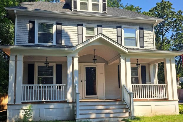 Two-story white house with a porch and dark shutters.