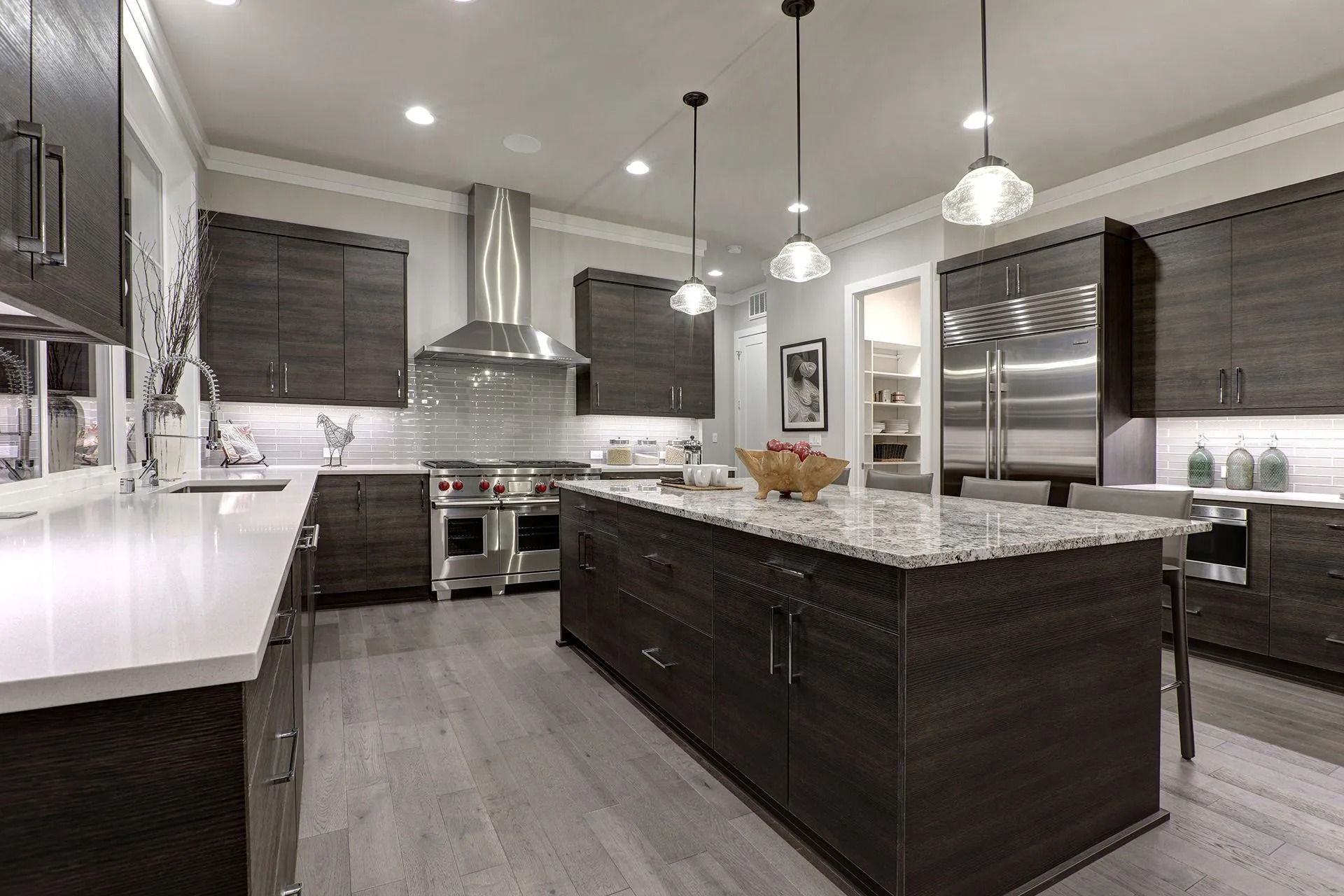 Modern kitchen with dark cabinetry, stainless steel appliances, and a large island.