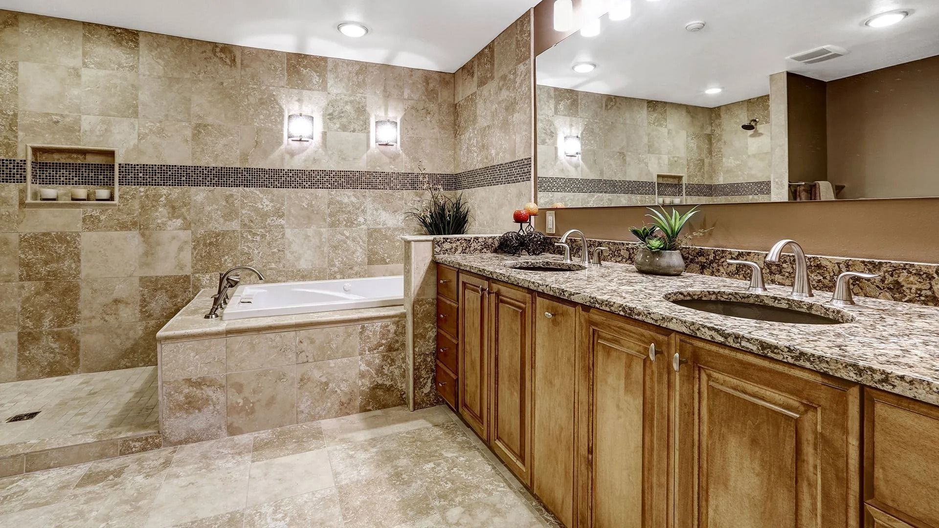 Bathroom with tan tile, wooden cabinets, a bathtub, and a double sink.