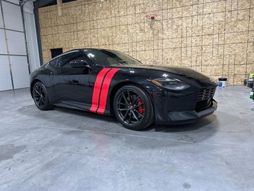 A black sports car with red stripes is parked in a garage.