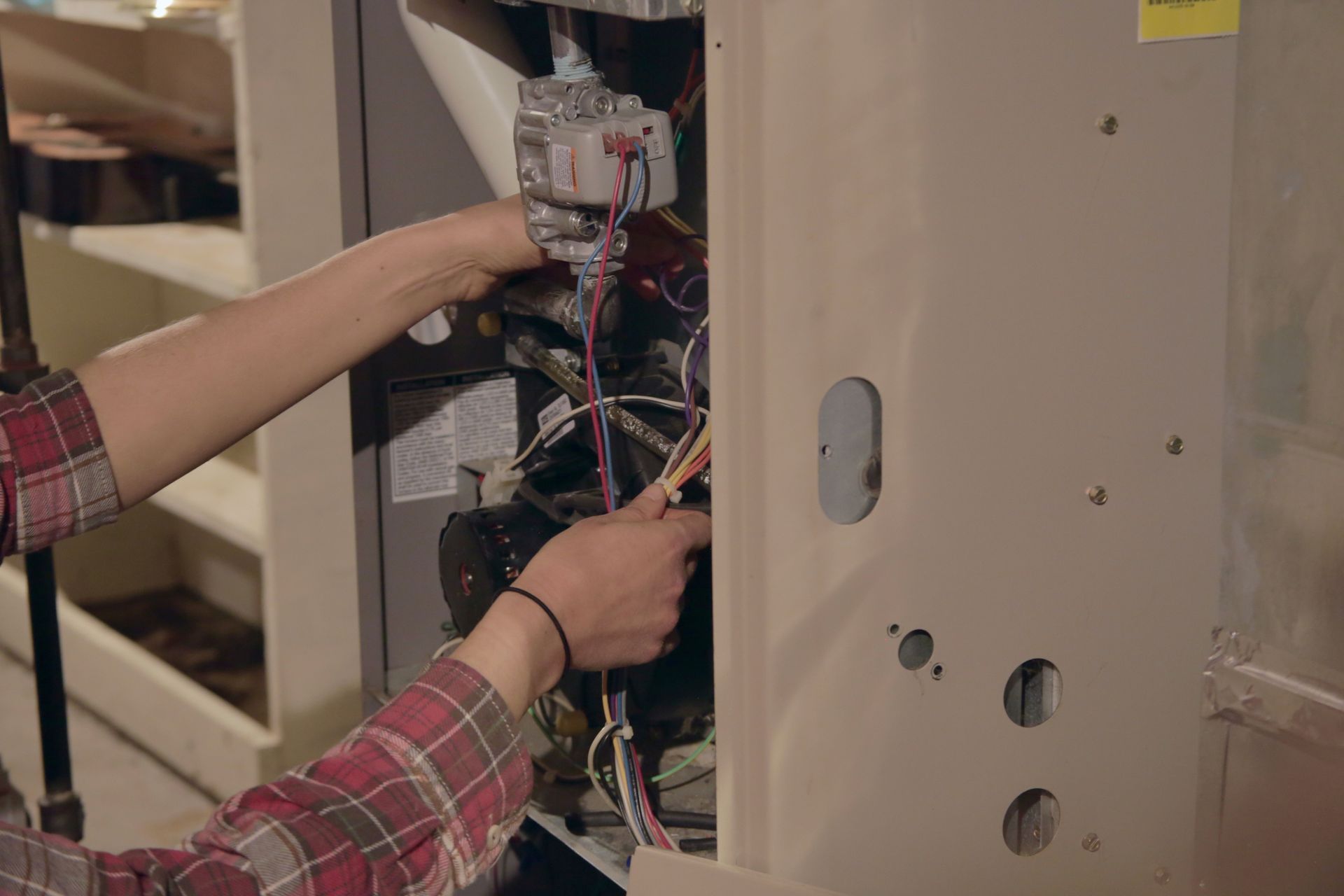 Person working inside an open electrical cabinet with exposed wires and panels