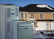 Two white utility cabinets in front of a beige house with a garage on a snowy day