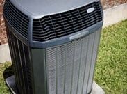 Outdoor air conditioning unit on grass beside a house wall