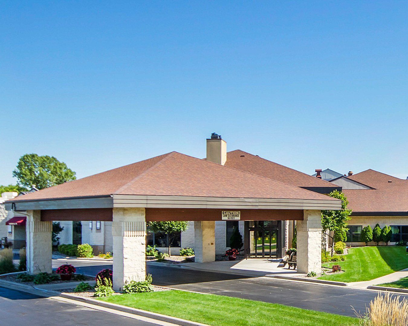 Covered entrance to a building with a brown roof and cream-colored pillars, clear blue sky.