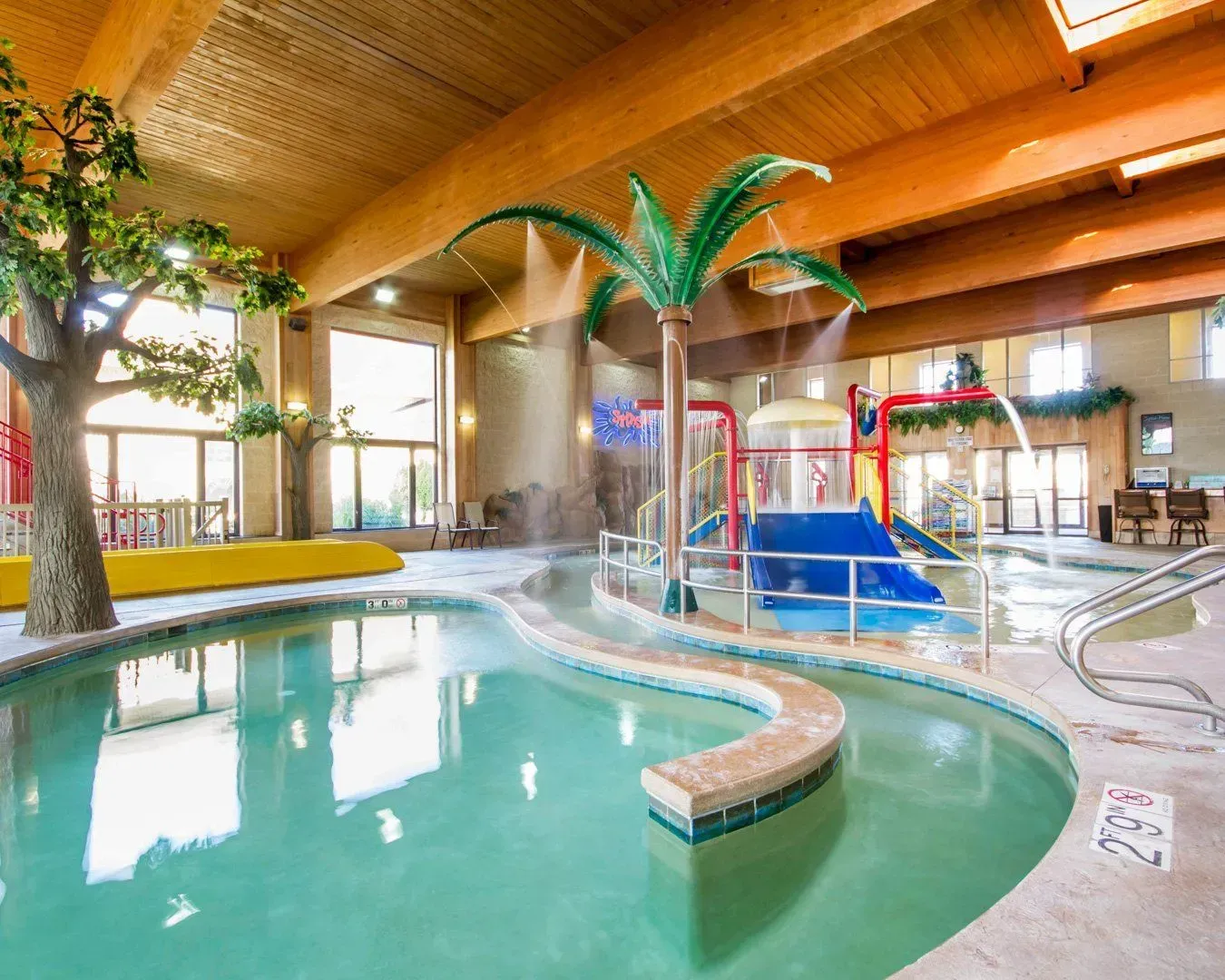 Indoor waterpark with palm trees, a slide, and a lazy river.