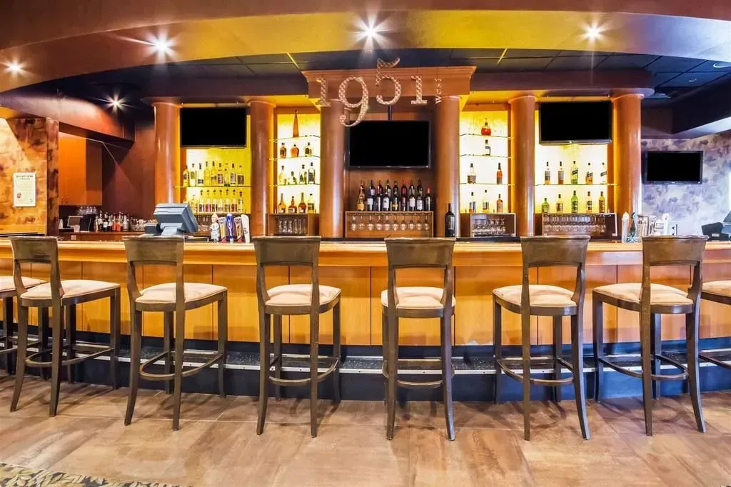 Bar with wooden bar stools and liquor bottles on display behind the counter. 