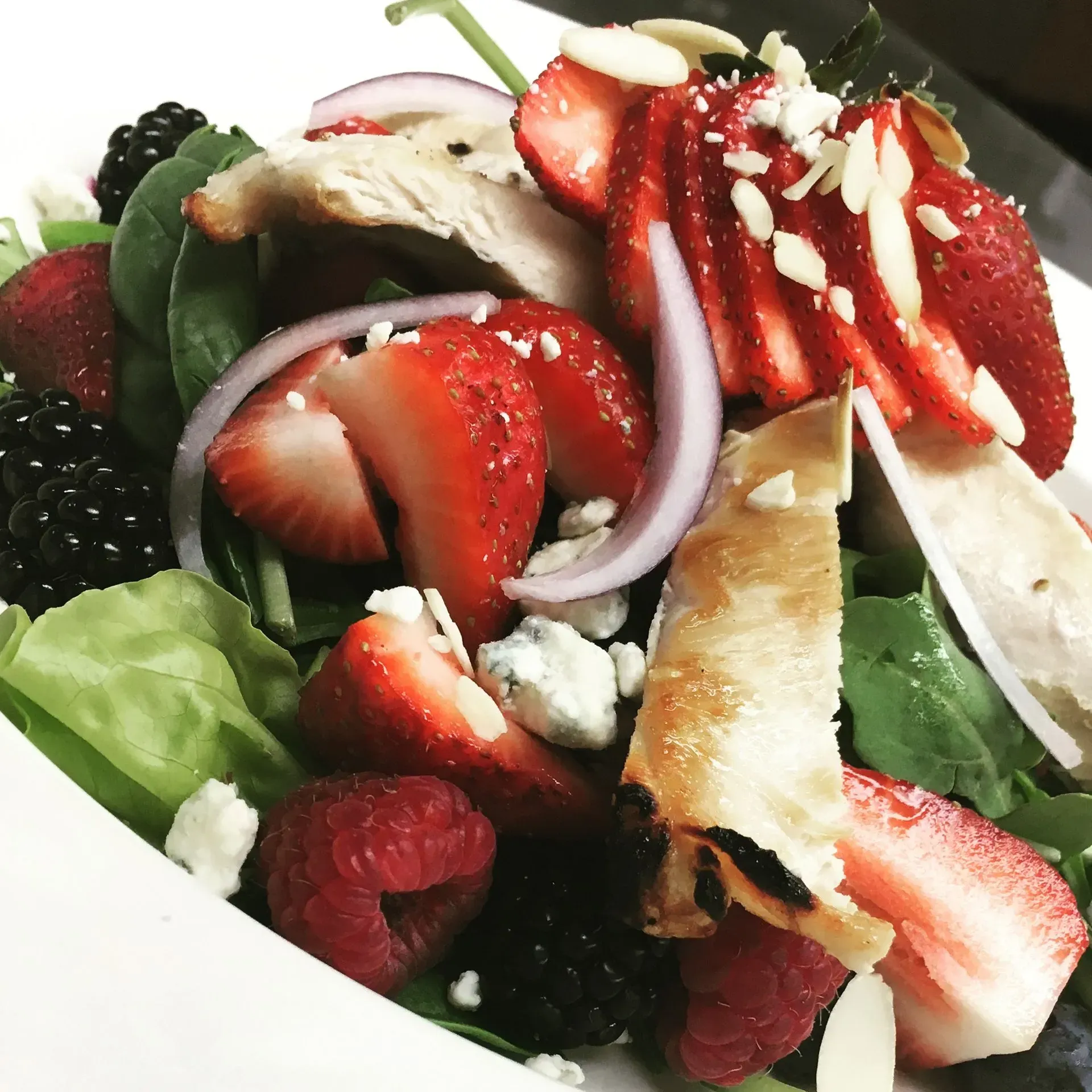 Salad with strawberries, blackberries, raspberries, red onion, chicken, blue cheese, and almonds.