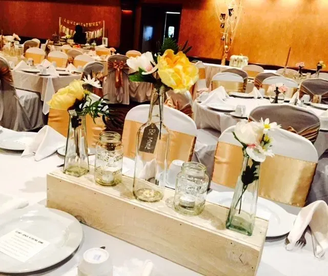 Wedding reception tables with floral centerpieces and gold chair sashes.