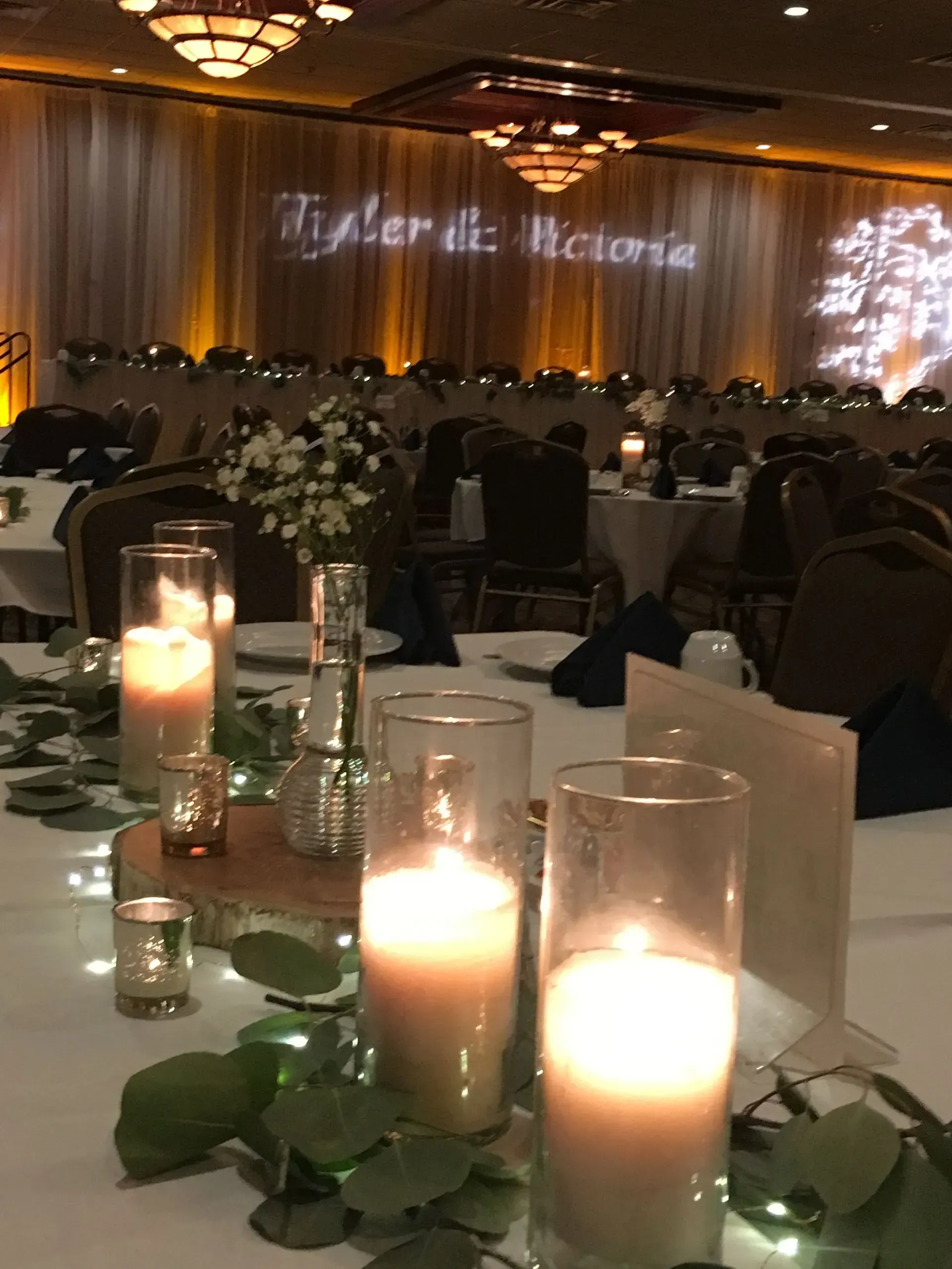 Wedding reception table setting with candles, greenery, and a floral centerpiece.