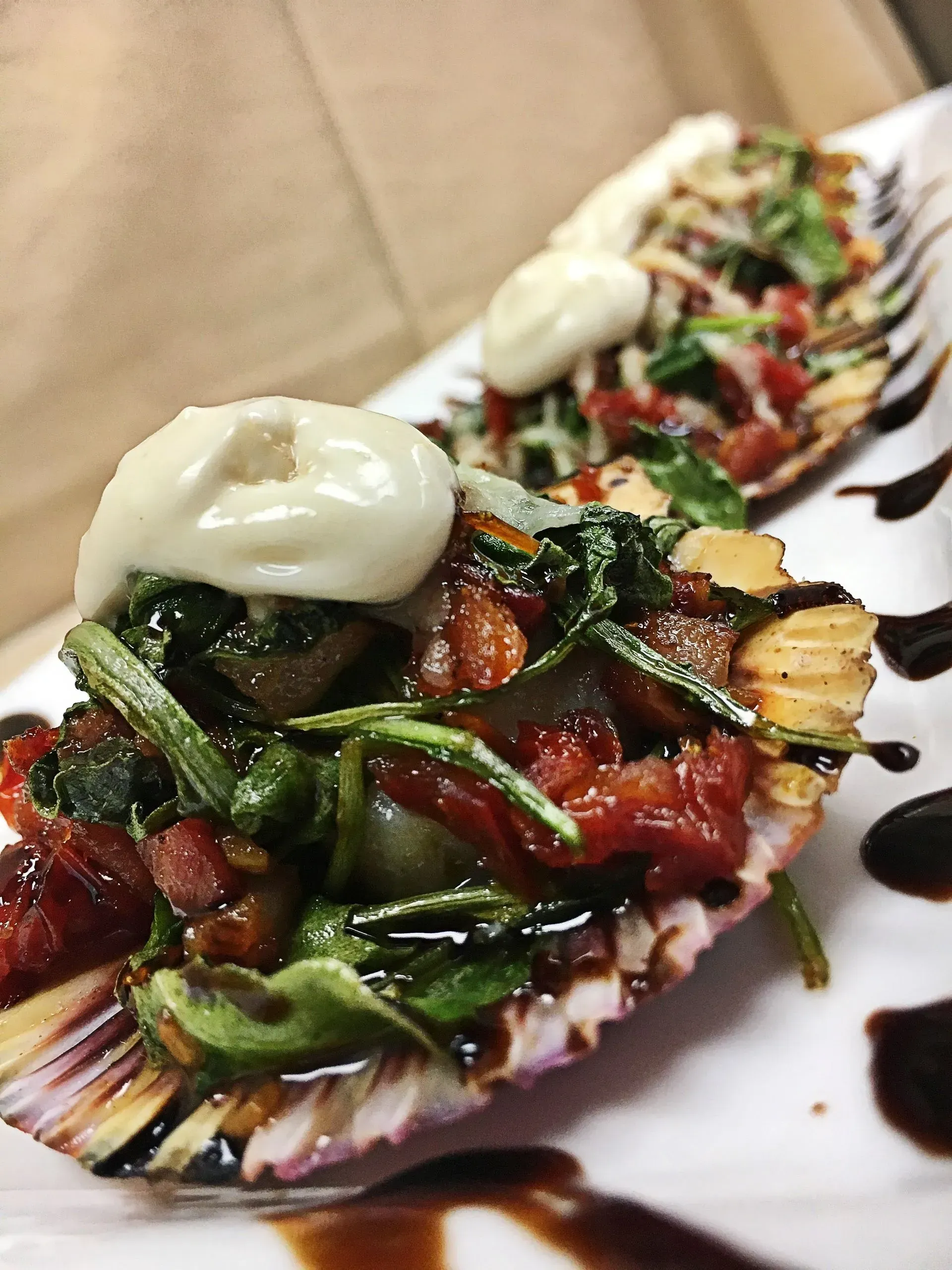 Endive shells filled with tomatoes, greens, and sauce, drizzled with balsamic glaze.