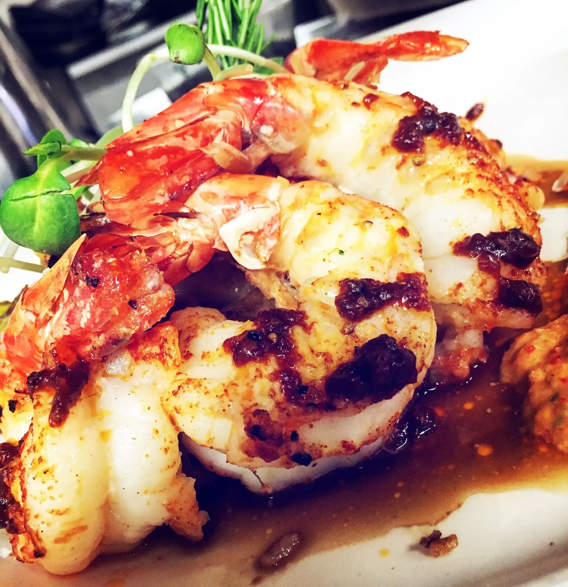 Grilled shrimp with sauce and microgreens.