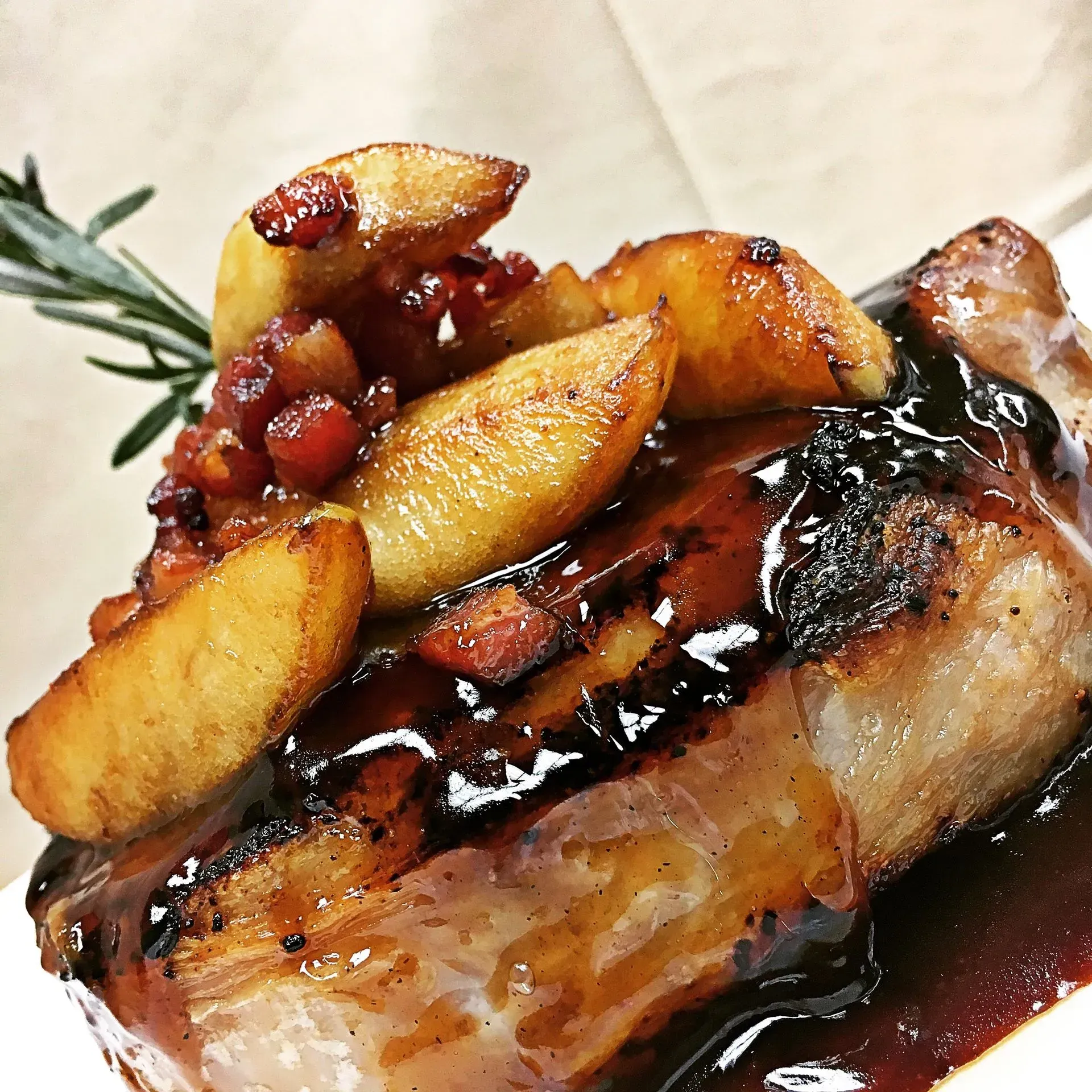 Pork chop with apple slices and a balsamic glaze, garnished with rosemary.