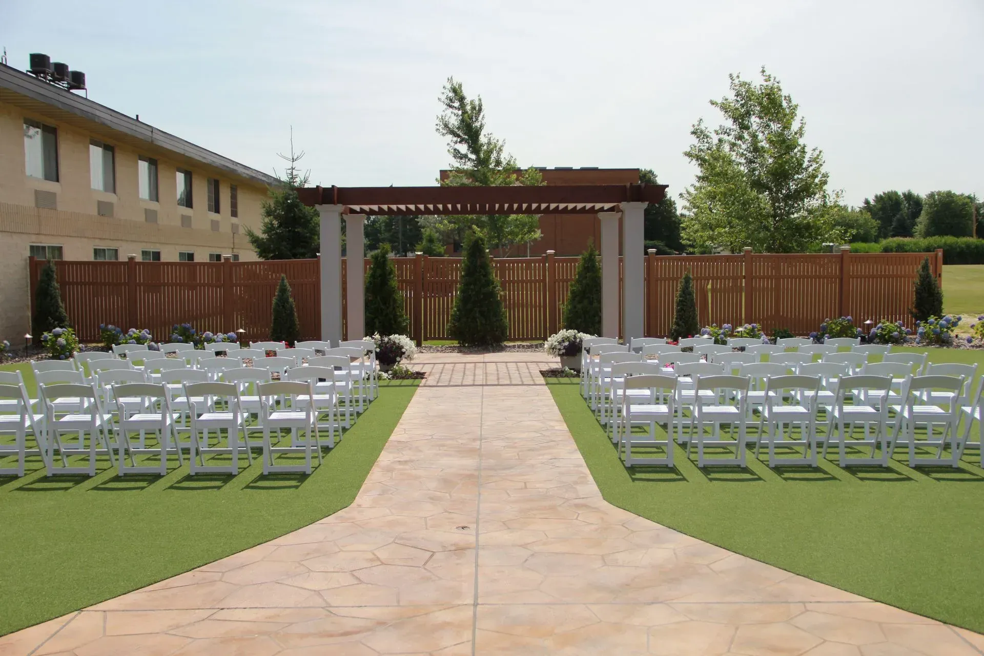 Wedding ceremony setup outdoors with rows of white chairs facing a decorated altar.