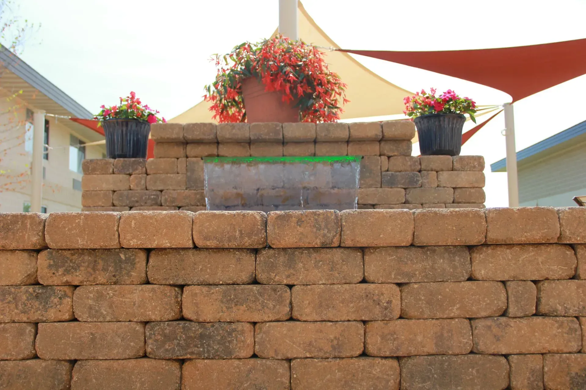 Brick wall with a built-in planter featuring flowers and a translucent container of green material.