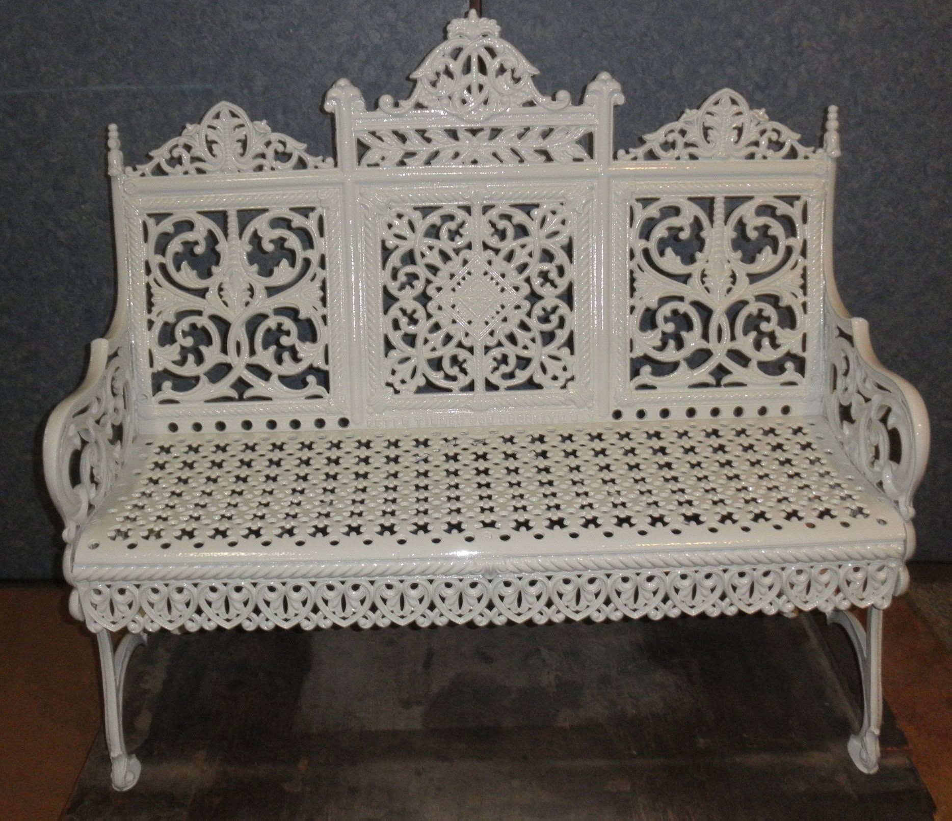 White ornate carved bench with lace-like backrest and seat on a dark background