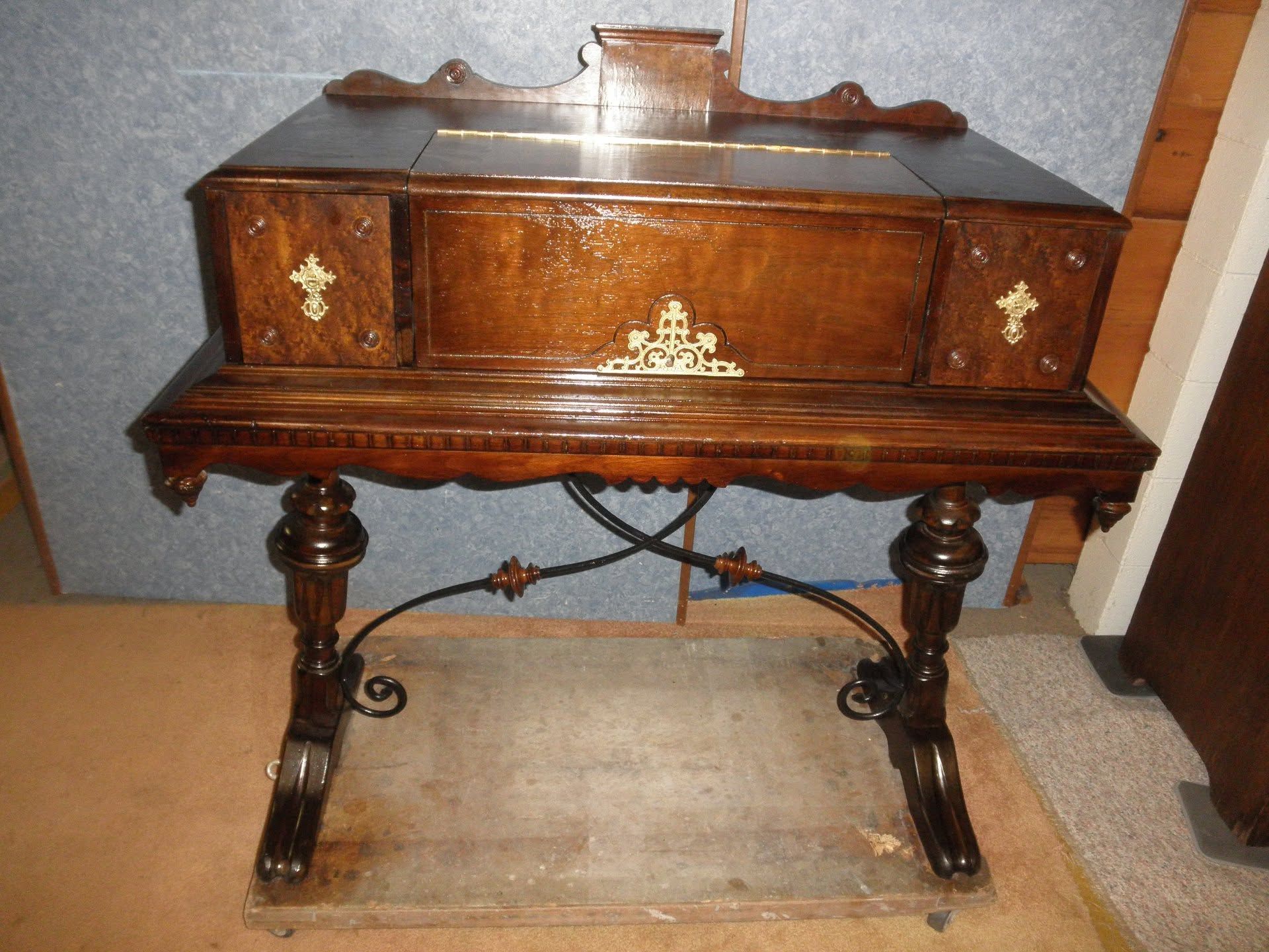 Dark wooden antique cabinet with ornate legs and brass details on a carpeted floor