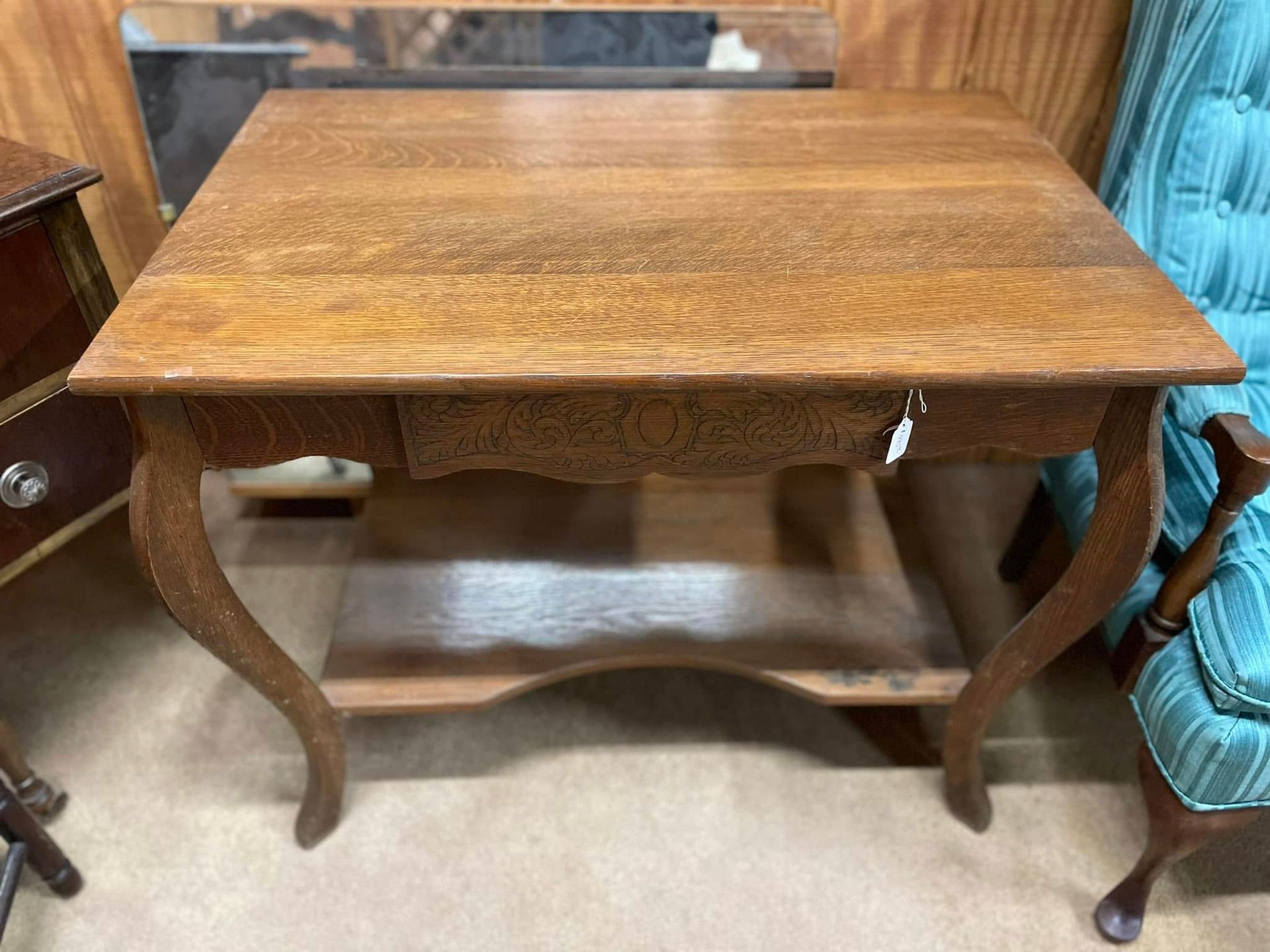 Wooden rectangular table with curved legs in a room, beside blue upholstered chairs.
