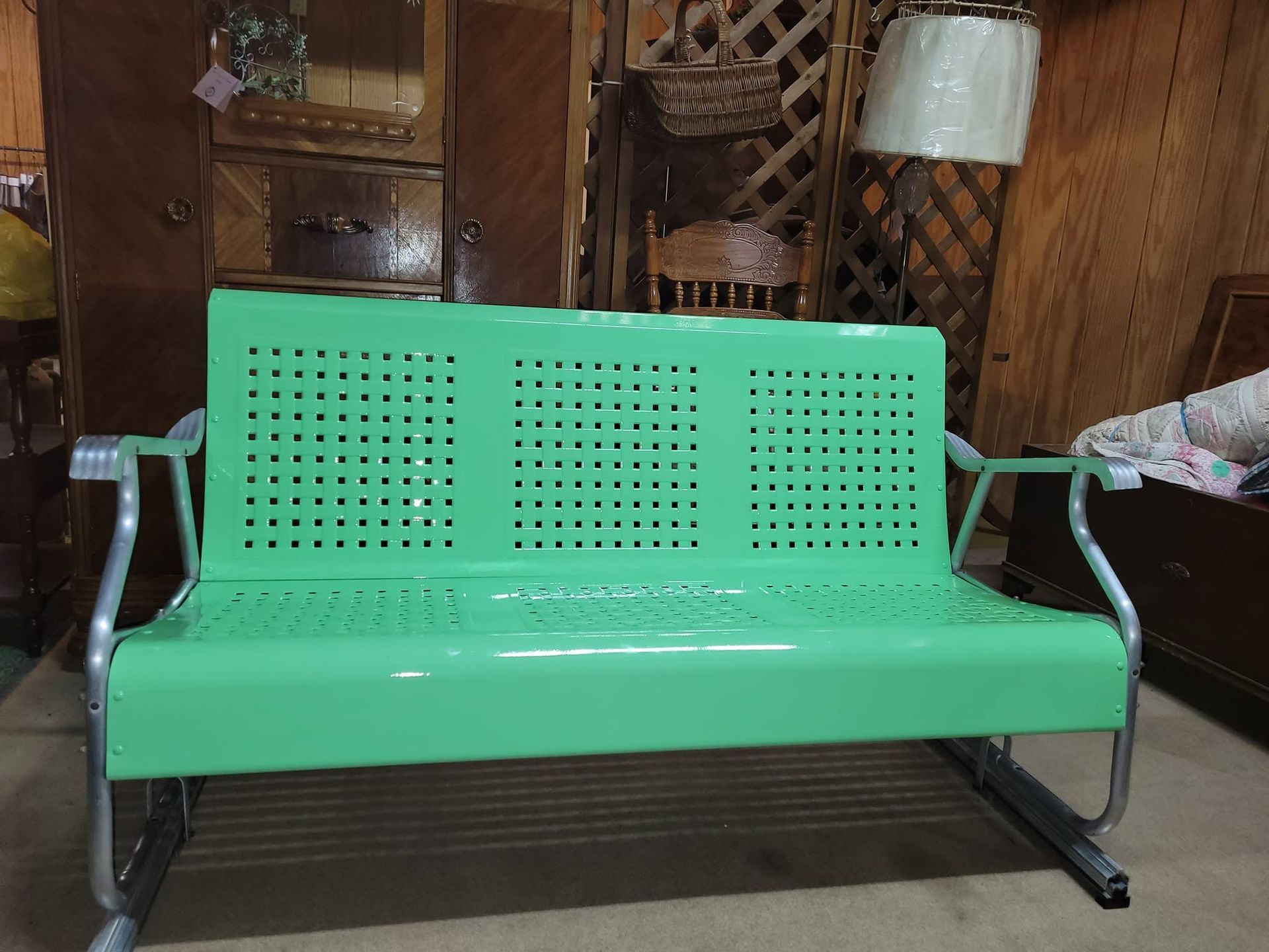 Mint-green metal bench with armrests in a wood-paneled room