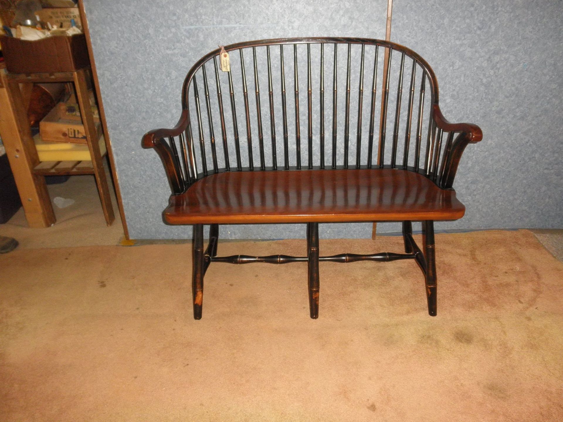 Wooden bench with curved back and arms on a beige carpet in a room