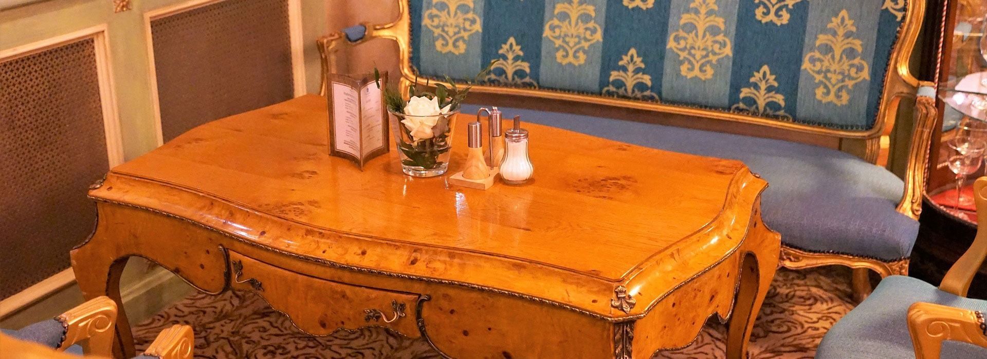 Ornate wooden table with flowers and condiments in a patterned dining room.