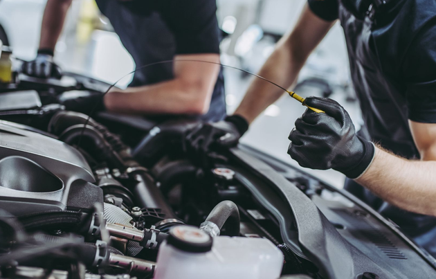 Mechanic using a tool to work on a car engine in a garage