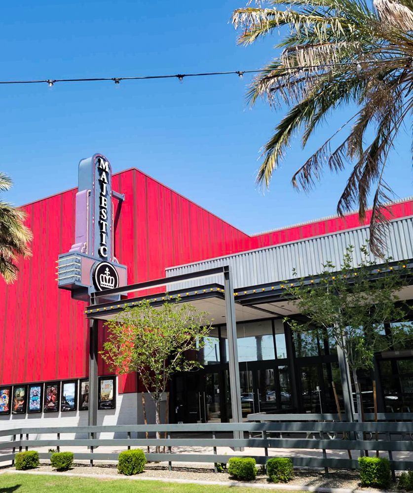 Exterior of the Harkins Theatres building with a red facade, sign, and palm trees.