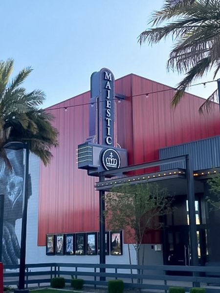 Majestic Theatre with a vertical sign, red walls, and palm trees.