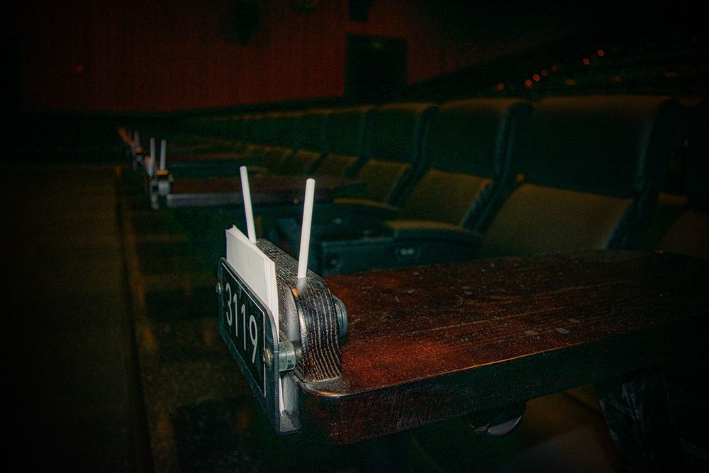 Empty movie theater with rows of seats and attached wooden tables.