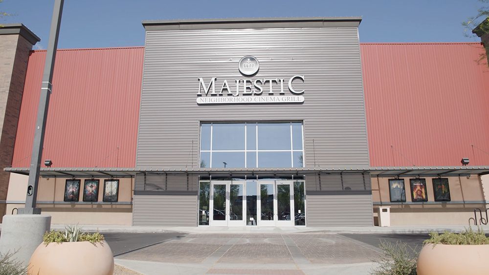Majestic movie theater entrance with red roof, gray facade, and glass doors.